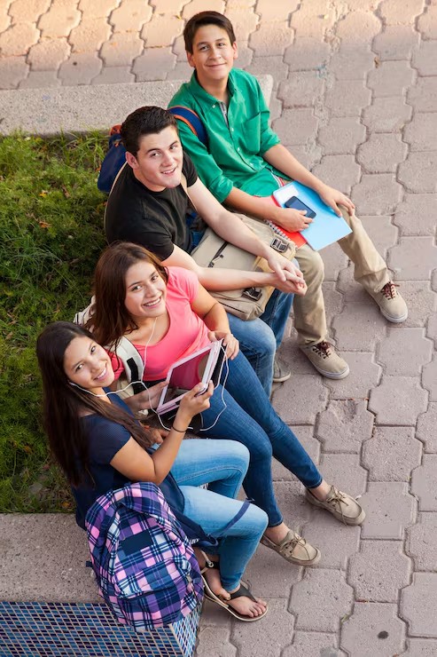 Grupo de estudiantes sonriendo, sentados con sus cuadernos y tablet
